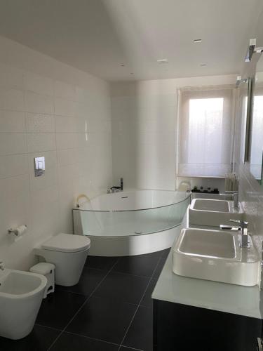 a bathroom with three sinks and a tub and a toilet at La Rosa nel Paese in Soveria Mannelli