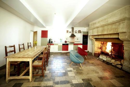 une cuisine avec une table en bois et une cheminée dans l'établissement La Ferme de Franqueville 'Big Gîte', à Sainte-Marie-du-Mont