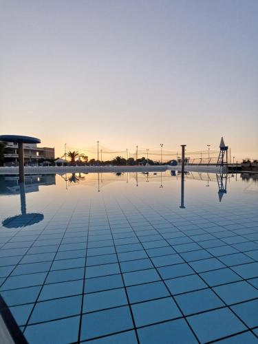 an empty pool with the sun setting in the background at Corvino Resort in Monopoli