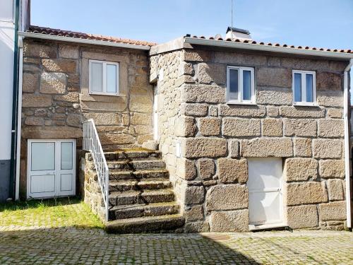 una casa in pietra con scale e due porte e un edificio di Casa do Tinte - Gouveia-Folgosinho a Vila Cortês da Serra