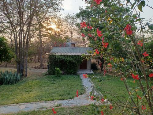 a small building in a garden with red flowers at Mikooka Estate in Chongwe