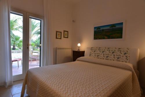 Un dormitorio con una cama y una puerta corrediza de vidrio. en Villa Torre Bianca - Luxury Home, en Manduria