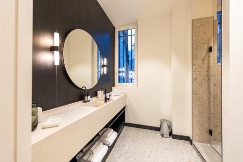 a bathroom with a sink and a mirror at Les Suites by Cave Vauban in Dijon