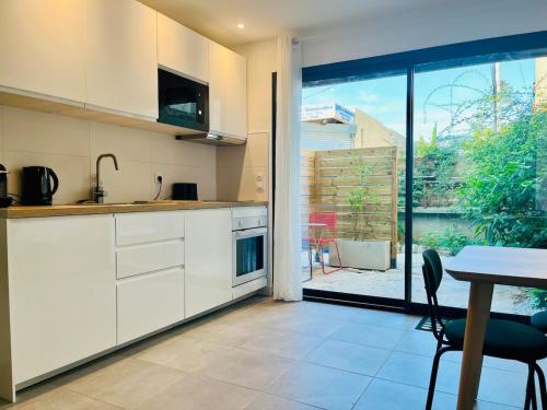 une cuisine avec des armoires blanches, une table et une fenêtre dans l'établissement Studio - terrace Quiet & Cozy, à Montpellier