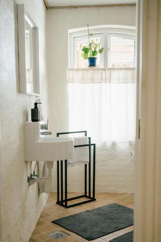 a white bathroom with a sink and a window at Det gamle hus ved søen in Gråsten
