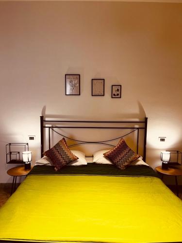 a bedroom with a yellow bed with three pictures on the wall at Sicilia Vacation rooms in Trapani