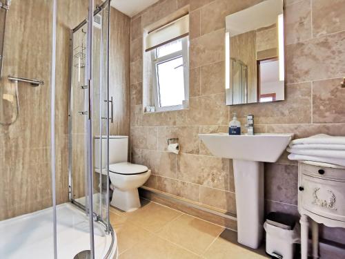 Un baño con inodoro, lavabo y ducha. en Glenview Luss, en Luss