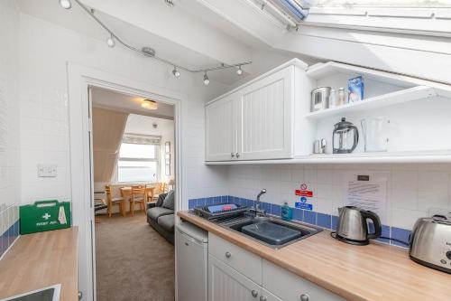 a kitchen with white cabinets and a sink at Beach Front flat in Aberdovey in Aberdyfi