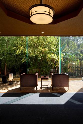 a lobby with two chairs and a table and trees at Koran no Yu Kinkouro in Ibusuki
