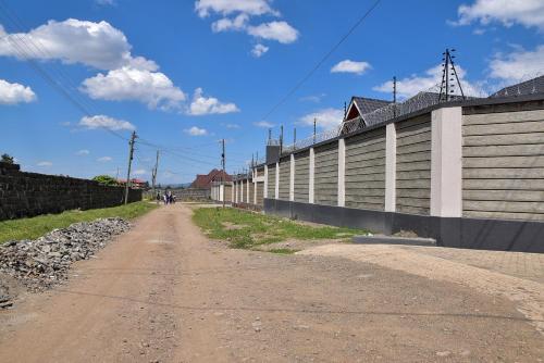 an empty dirt road next to a wall at Barnabas Nakuru Comfy Homestays in Nakuru