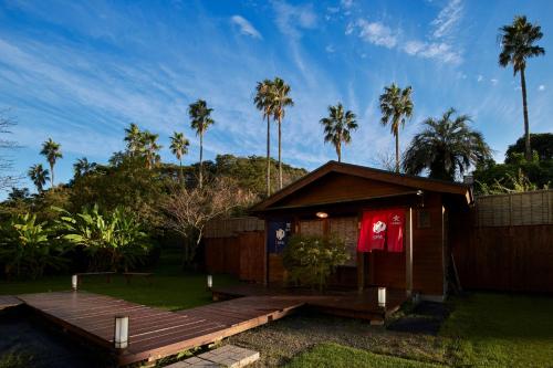a house with a wooden deck and palm trees at Koran no Yu Kinkouro in Ibusuki