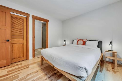 a white bedroom with a large bed and a wooden floor at Stunning Mountain Gem with Hot Tub Near Palisades in Olympic Valley