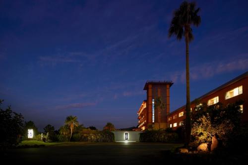 a hotel at night with a palm tree and a building at Koran no Yu Kinkouro in Ibusuki