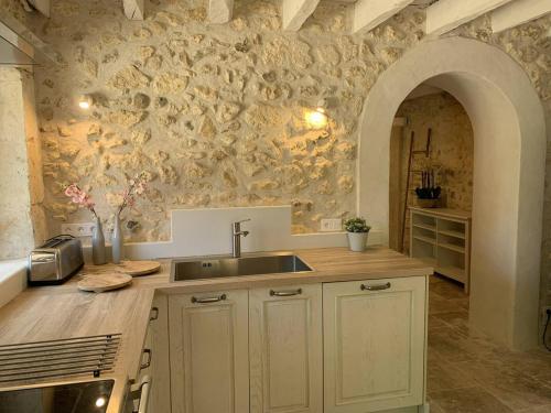 une cuisine avec un évier et un mur en pierre dans l'établissement Le Cottage Lascaux, à Bourrou