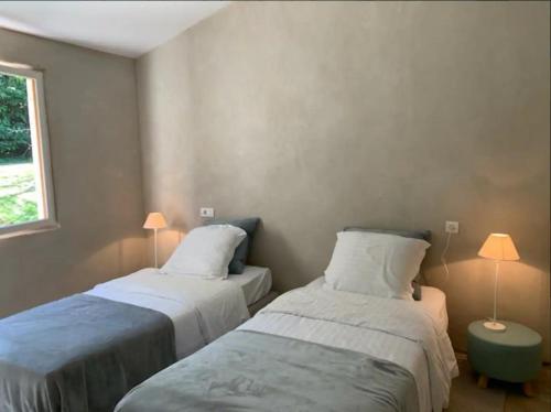 - 2 lits dans une petite chambre avec 2 lampes dans l'établissement Le Cottage Lascaux, à Bourrou