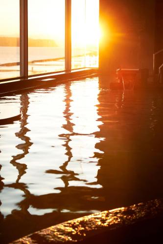 a pool of water with the sun setting in the background at Koran no Yu Kinkouro in Ibusuki