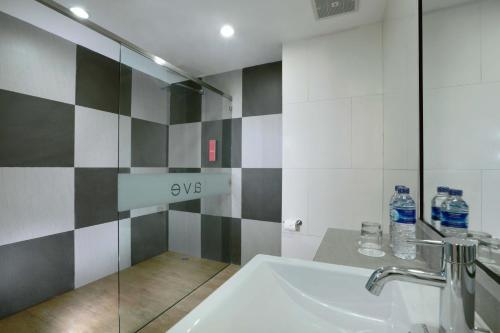 a bathroom with a sink and a shower with water bottles at favehotel Ahmad Yani Banjarmasin in Banjarmasin