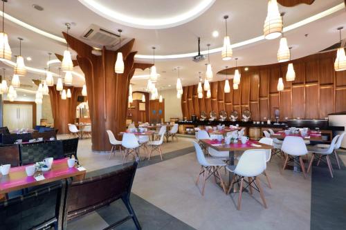 a restaurant with tables and white chairs and a bar at favehotel Ahmad Yani Banjarmasin in Banjarmasin