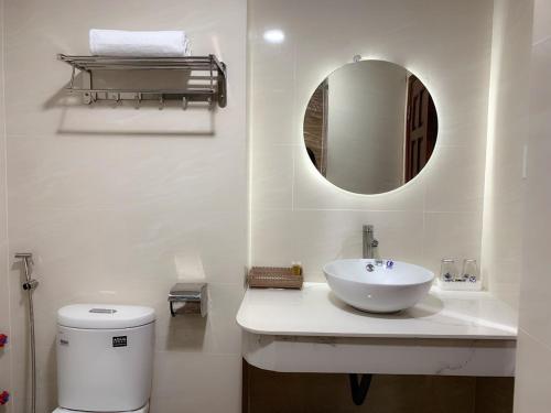 a white bathroom with a sink and a mirror at Khách sạn Trung Hiếu Vũng Tàu in Vung Tau