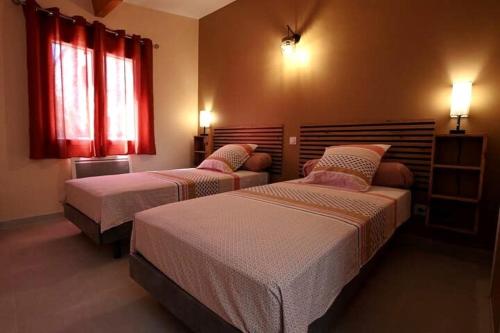 - 2 lits dans une chambre avec des rideaux rouges dans l'établissement Gîte le pontilh, à Saint-Privat