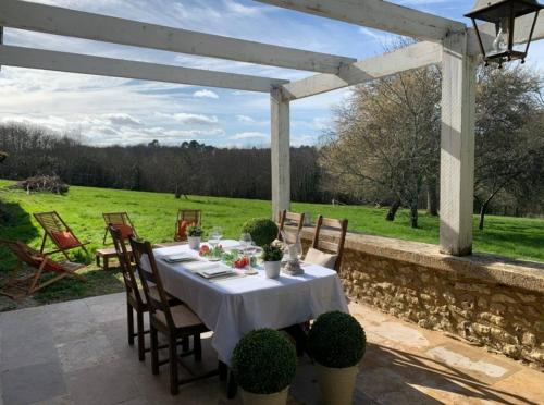 - une table et des chaises sur une terrasse avec vue sur un champ dans l'établissement Le Cottage Monbazillac, à Bourrou
