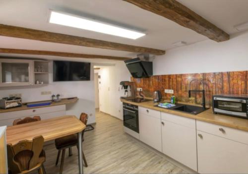 a kitchen with white cabinets and a wooden table at Numero1-Pension und Cafe in Rübeland