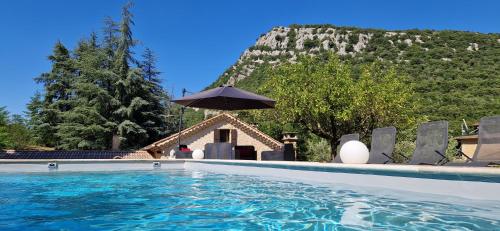 - une piscine avec un parasol en face d'une montagne dans l'établissement Gîte de Chanabière, à Banne