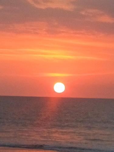 a sunset over the ocean with the sun in the sky at The Cozy Glass House by the Sea in Bauang