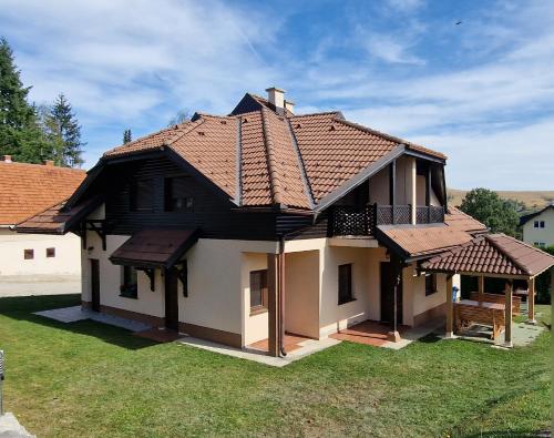 a house with a tiled roof on a yard at Zlatiborska Belina / Zlatibor White in Zlatibor