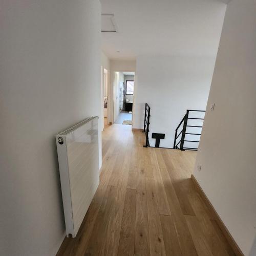 - un couloir avec des murs blancs et du parquet dans l'établissement Villa Maison 5 chambres, à Vitry-en-Artois