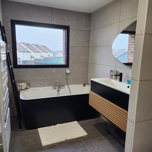 une salle de bain avec une baignoire, un lavabo et une fenêtre dans l'établissement Villa Maison 5 chambres, à Vitry-en-Artois