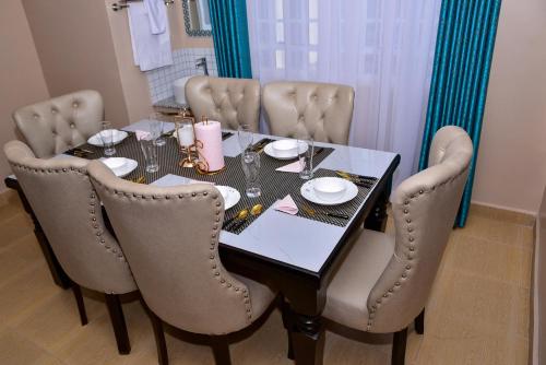a dining room table with chairs and a black table and a table at Barnabas Nakuru Comfy Homestays in Nakuru
