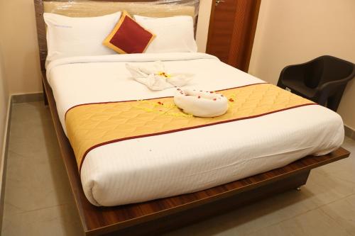 a bed with white sheets and flowers on it at Hotal Virinchi Ultra Comforts - Good Rooms - Brand New Building in Tirupati