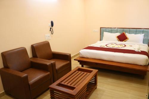 a bedroom with a bed and a chair and a table at Hotal Virinchi Ultra Comforts - Good Rooms - Brand New Building in Tirupati