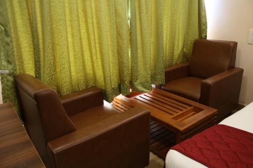 a hotel room with two chairs and a bed at Hotal Virinchi Ultra Comforts - Good Rooms - Brand New Building in Tirupati
