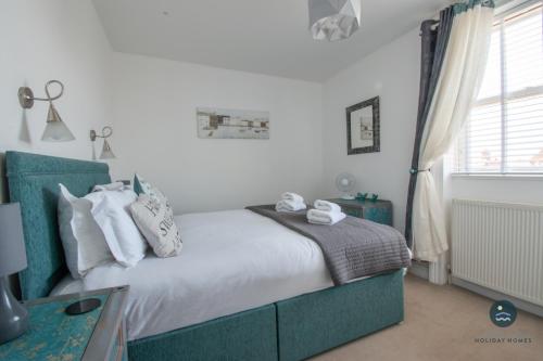 a bedroom with a bed with white sheets and pillows at Bay Retreat - Esplanade sea views parking in Weymouth