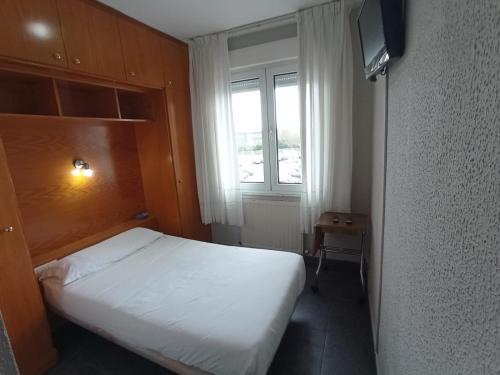 a small bedroom with a bed and a television at Puente Azud in Avilés