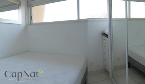 La salle de bains blanche est pourvue d'une fenêtre et d'un lavabo. dans l'établissement CapNat - Village Naturiste - Port Nature - Appartement 2 pièces - Le Chardonnay, au Cap d'Agde