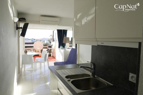 une cuisine avec un évier et une table avec des chaises dans l'établissement CapNat - Village Naturiste - Port Nature - Appartement 2 pièces - Le Chardonnay, au Cap d'Agde