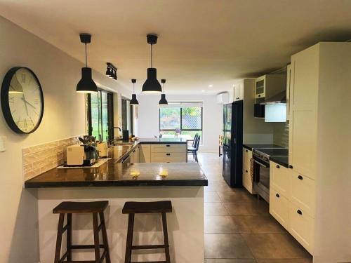 a kitchen with two bar stools and a clock on the wall at The Mountain House in Mount Tamborine