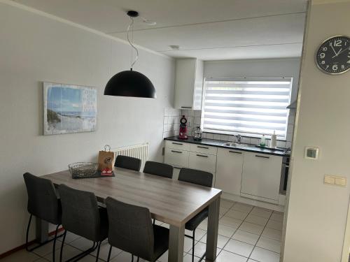 a kitchen with a table and chairs and a clock at Ferienhaus Fridolin Fort Soleil 27, Breskens Zeeland in Breskens