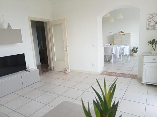 a white living room with a tv and a table at Al frutteto in San Pietro di Feletto