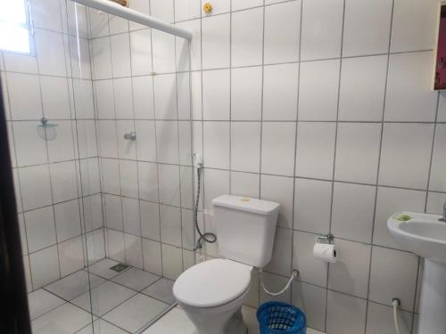 a white bathroom with a toilet and a sink at Aquarela Suítes in Piúma
