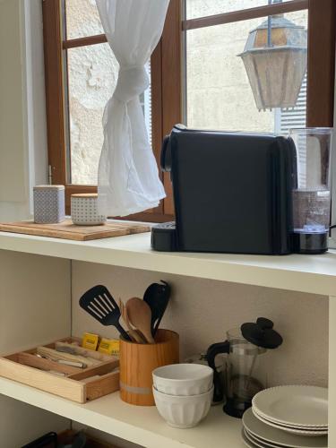 - une étagère avec des ustensiles de cuisine et une boîte dans l'établissement Logement Cosy à Périgueux avec 2 Chambres, Wifi fibre, à Périgueux