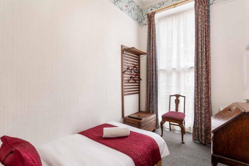 a bedroom with a bed and a chair and a window at St Athans Hotel in London