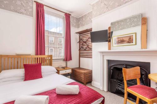 a bedroom with a bed and a fireplace at St Athans Hotel in London