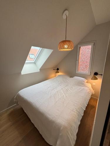 une chambre avec un lit blanc et une fenêtre dans l'établissement L'appartement, à Gruson