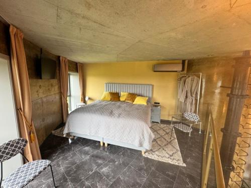 a bedroom with a bed with yellow pillows on it at Watertorenhotel WADHOOG in Sint Jacobiparochie