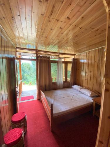 a bedroom with a bed in a wooden house at Shangdhan Pine Homestay in Sāmthar