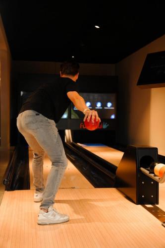a man is playing bowling on a bowling alley at LuxChalet Ferienhaus ELLA mit Aussicht auf die Ijssel im Ferienpark mit Pool und Strand Holland Niederlande in Lathum